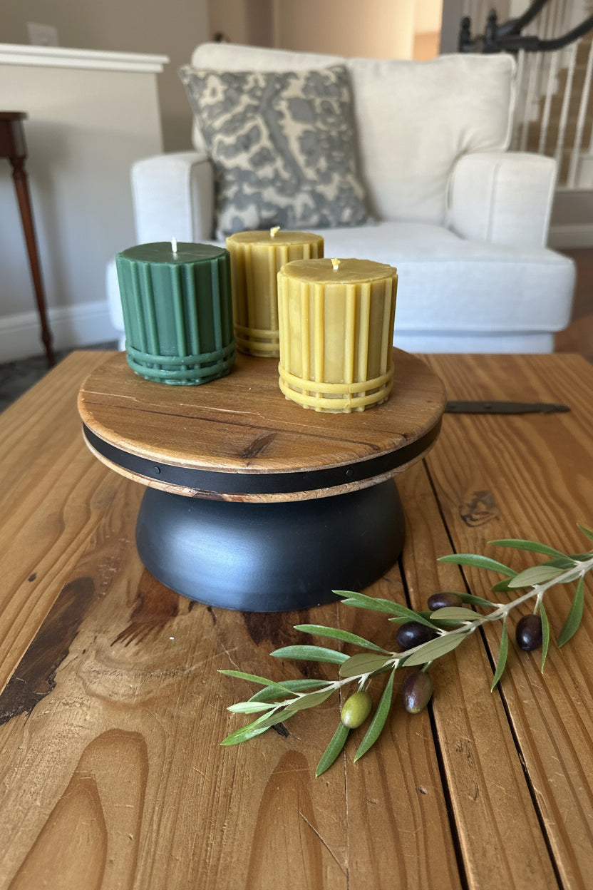 Stately Ribbed California Beeswax Pillar candle with Bands like Bourbon glass on wooden platform