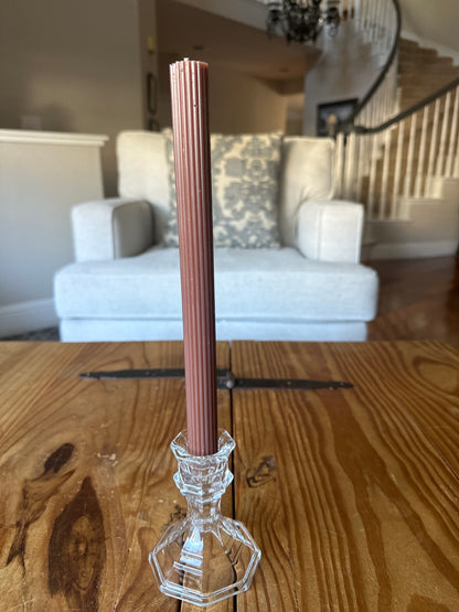 Brown ribbed taper dinner candle on rustic  wooden table in home.