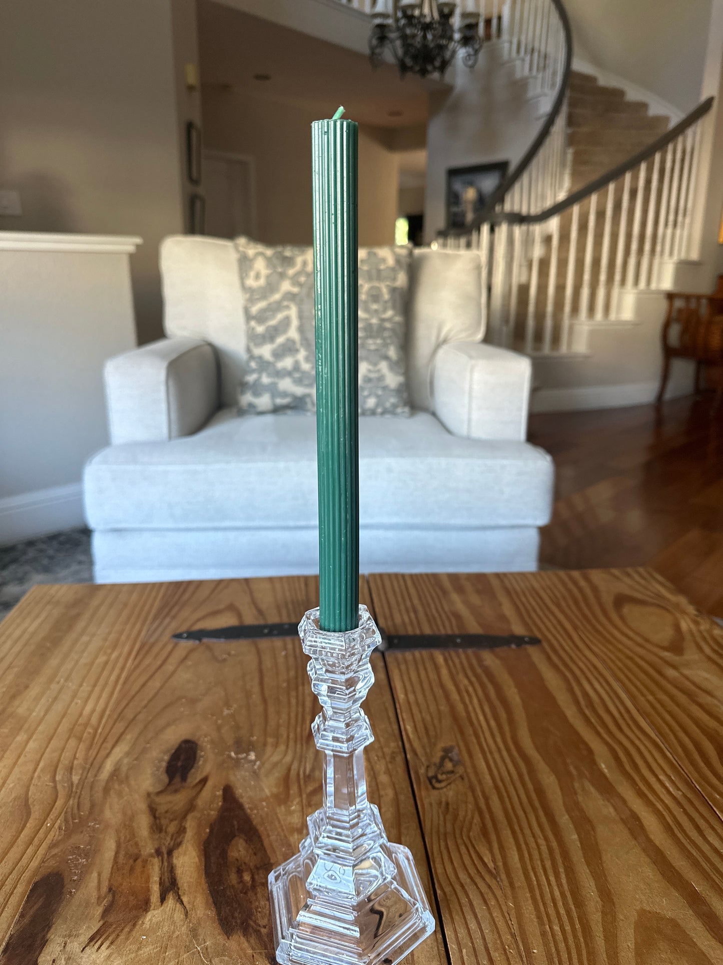 Green ribbed taper candle on rustic wooden table in home
