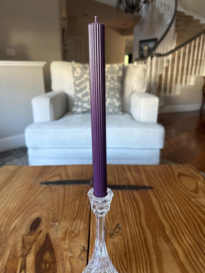 Purple ribbed taper dinner candle on rustic wooden table in a home.